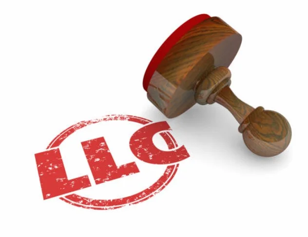 Bir beyaz kağıt üzerinde yan yatık duran bir mühür , kağıt üzerine yeni basılan kırmızı renkte bir LLC yuvarlak içinde mühürlenmiş